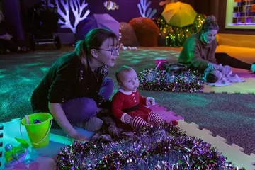 Mothers and babies taking part in Baby Sensory Stories at Christmas time at London Zoo 