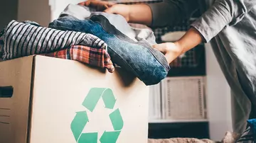 A woman placing clothes in a cardboard recycling box