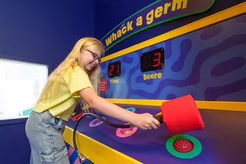 A girl wearing a yellow t-shirt playing whack a germ