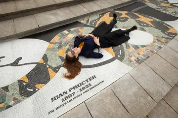 Linder wearing black clothing and sunglasses lies on the mosaic