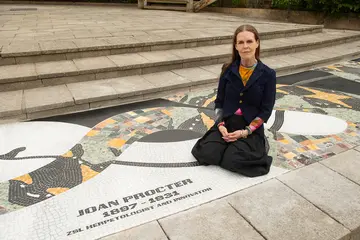 Linder wearing black clothing sitting on a mosaic