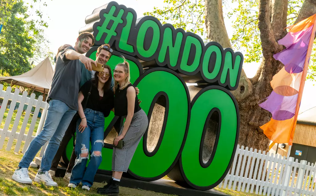 Group taking a selfie in front of giant #LondonZoo sign