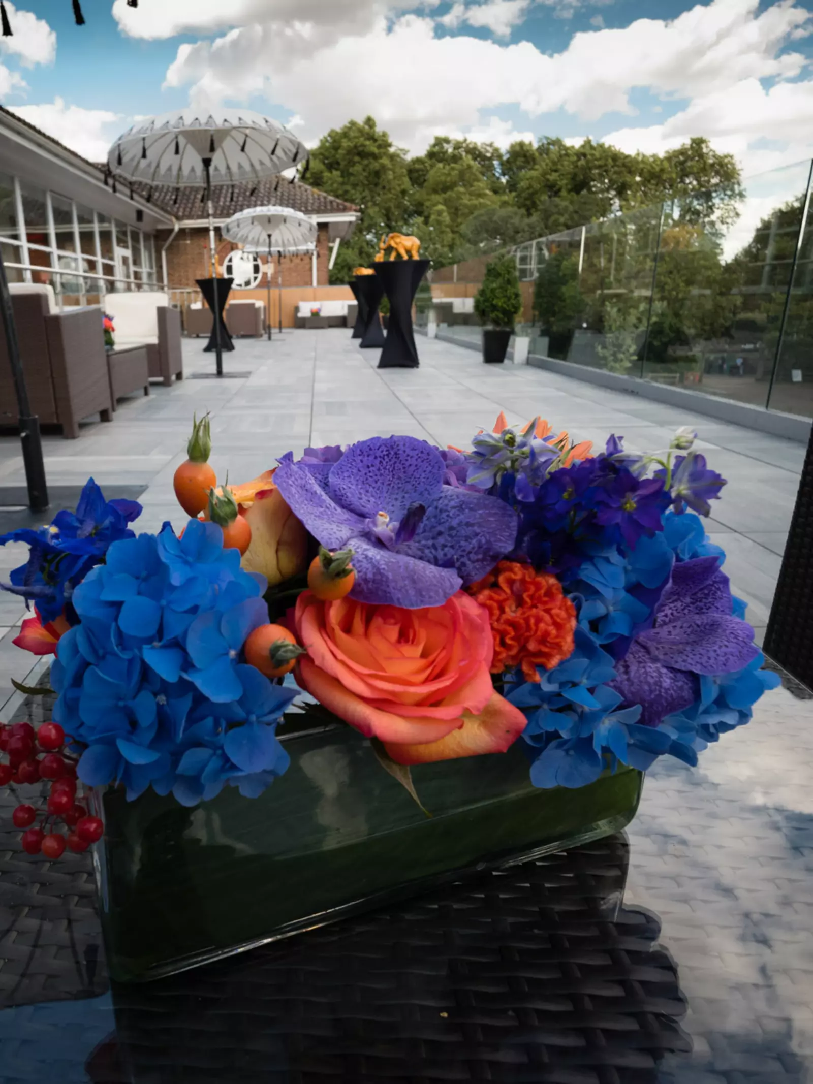 Purple, orange and blue flowers in a vase on a table on the Prince Albert Suite Terrace