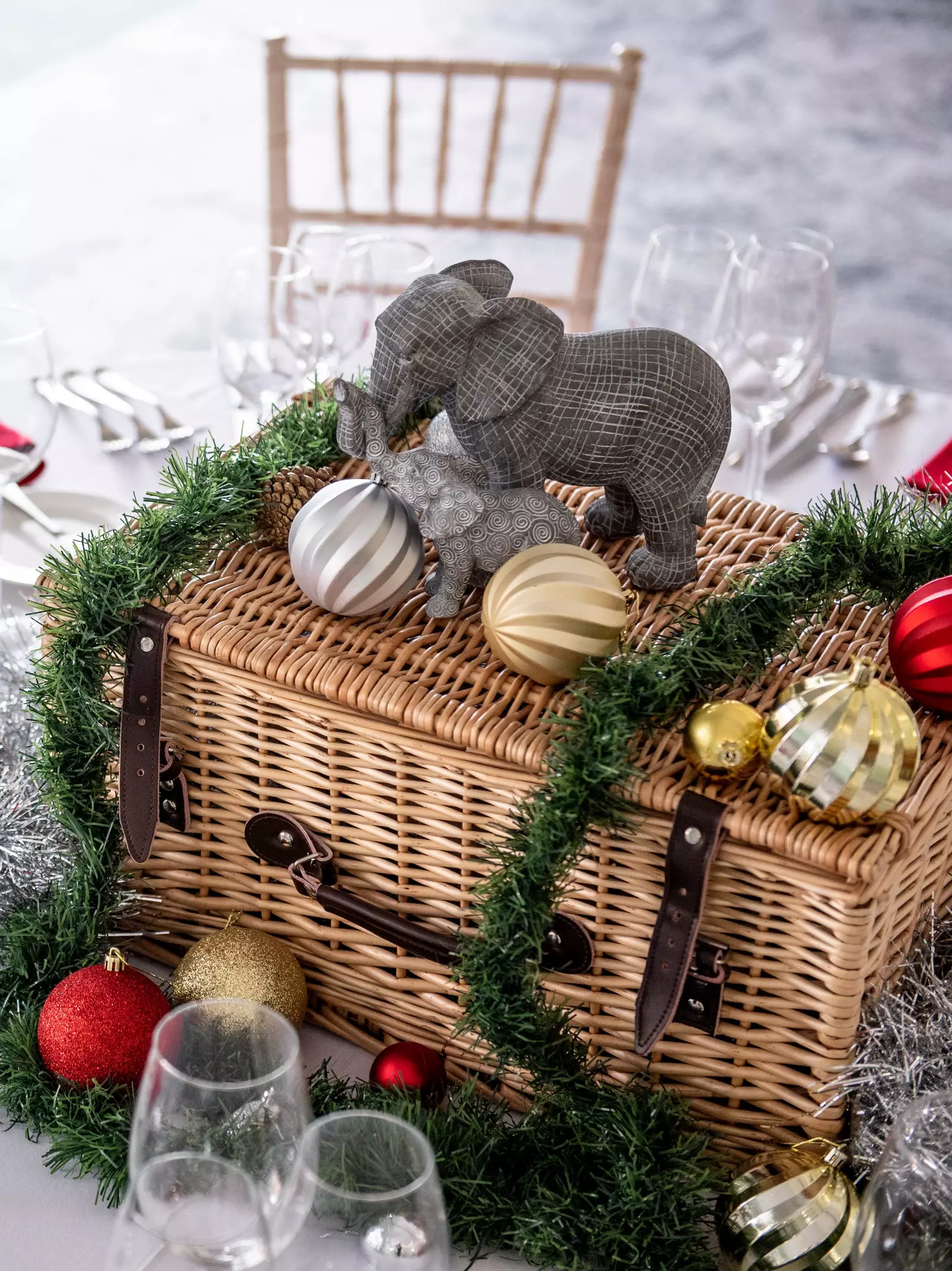 A Christmas party table setting with a hamper in the centre