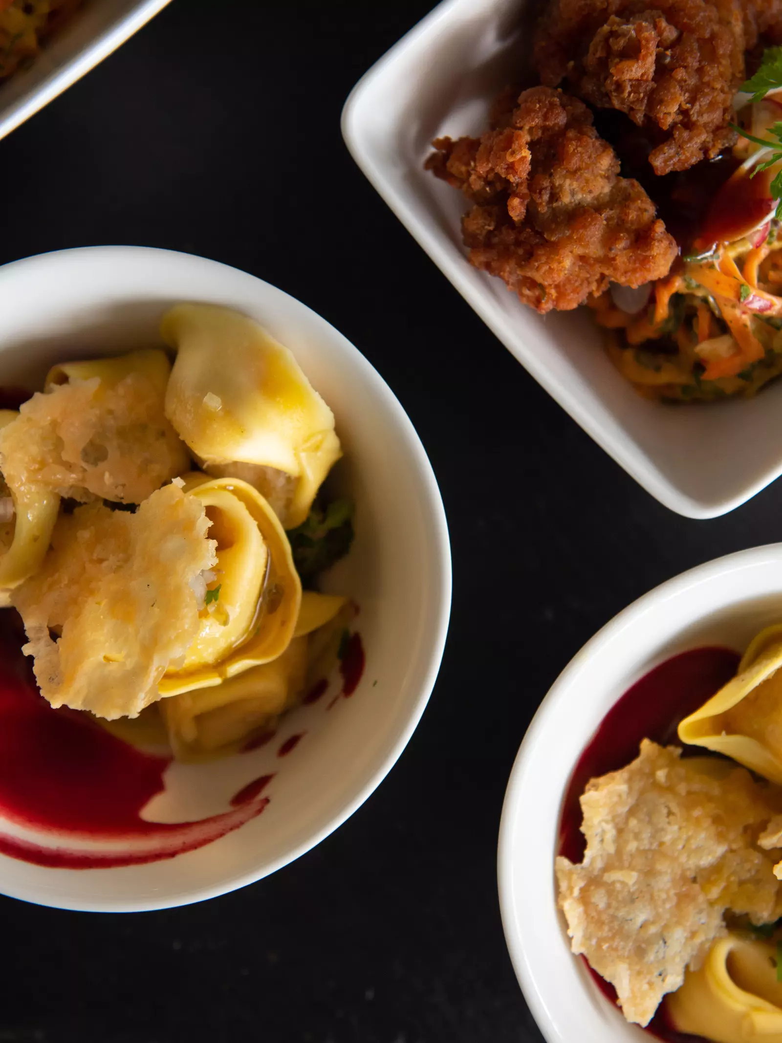 Bowls of tortellini and bowls of a fried chicken dish on a table 