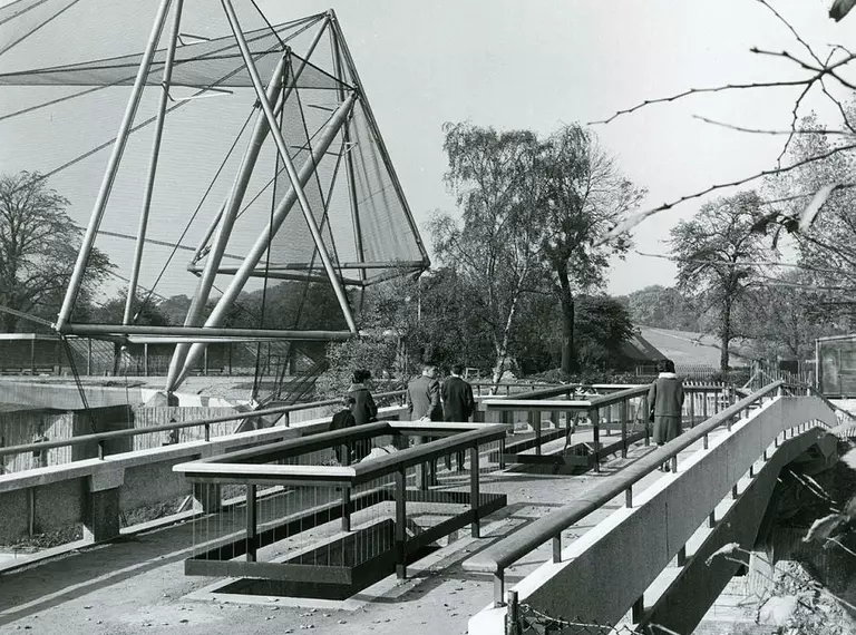 The Snowdon Aviary from the West Footbridge. There are visitors crossing the bridge. London Zoo, 1964.