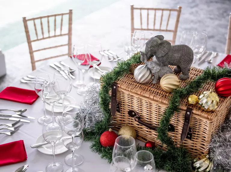 A Christmas party table setting with a hamper in the centre